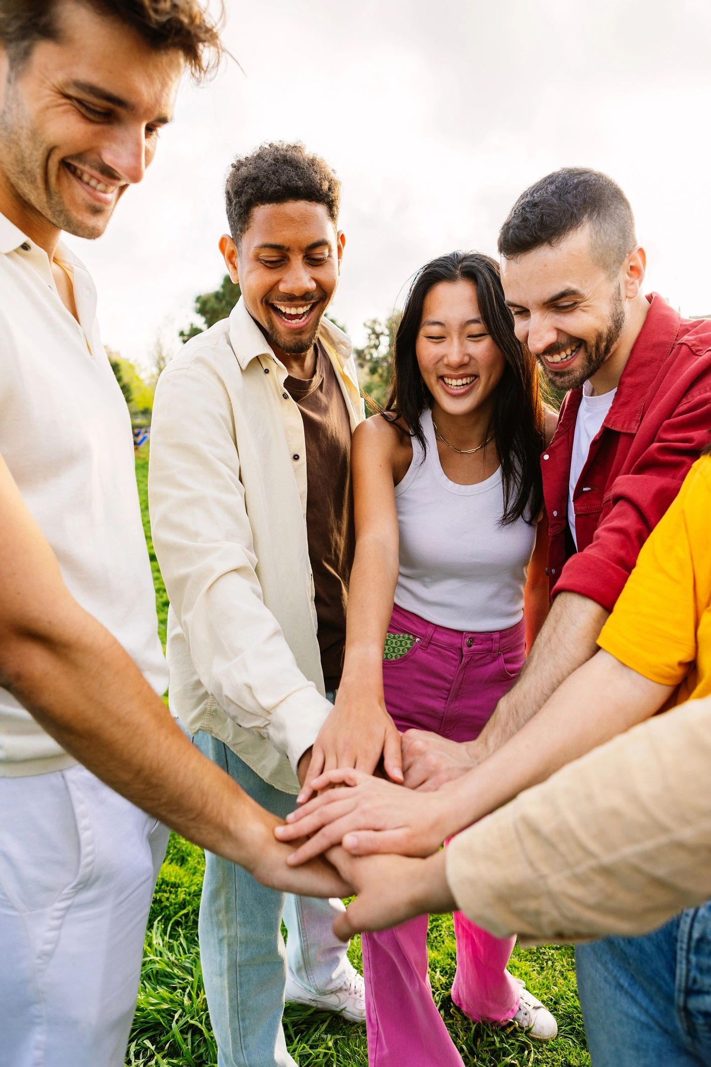 Multiracial young friends stacking hands in a park