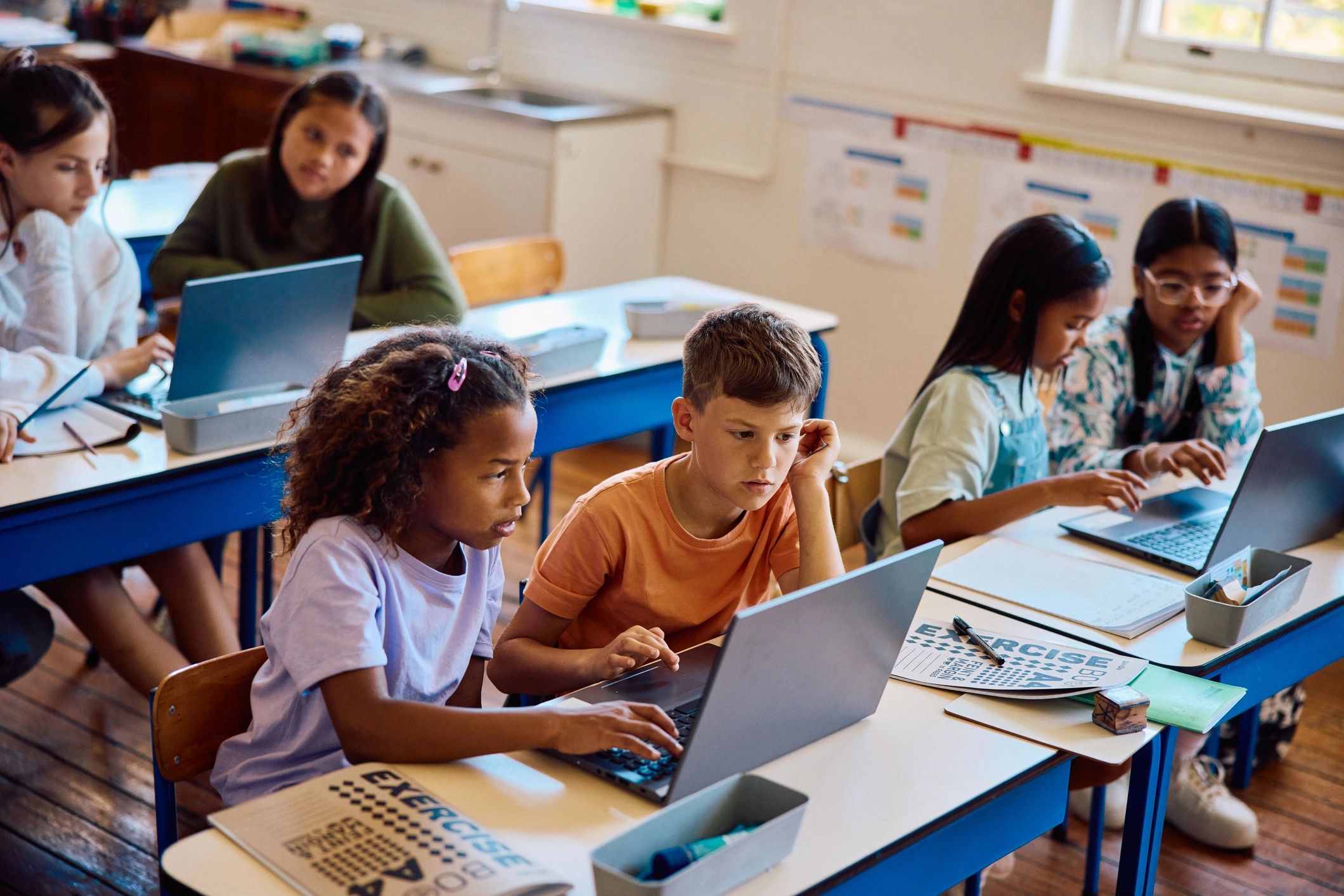 Elementary school children using laptops in teams in a classroom